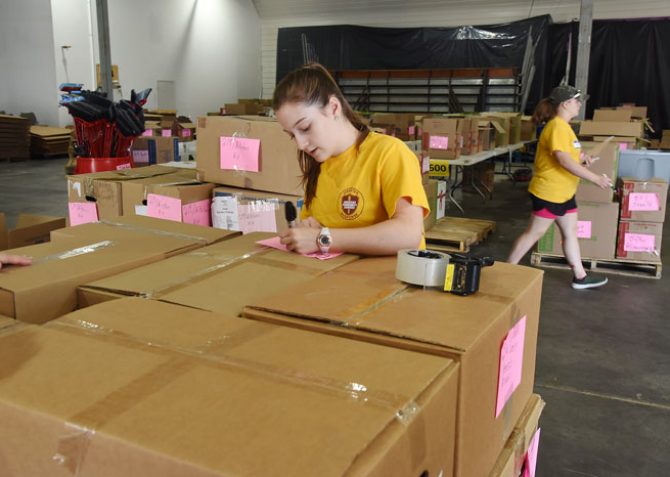 woman labeling cardboard boxes in warehouse